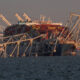 A cropped image showing a cargo ship with the bridge collapsed around it.