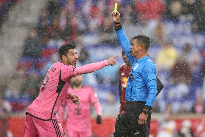 Referee Rafael Santos shows a yellow card to Inter Miami CF forward Luis Suarez (9) in the first half against the New York Red Bulls at Red Bull Arena in Harrison, New Jersey on Saturday, March 23, 2024.