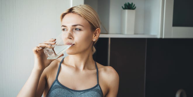 Woman drinking water at home in kitchen