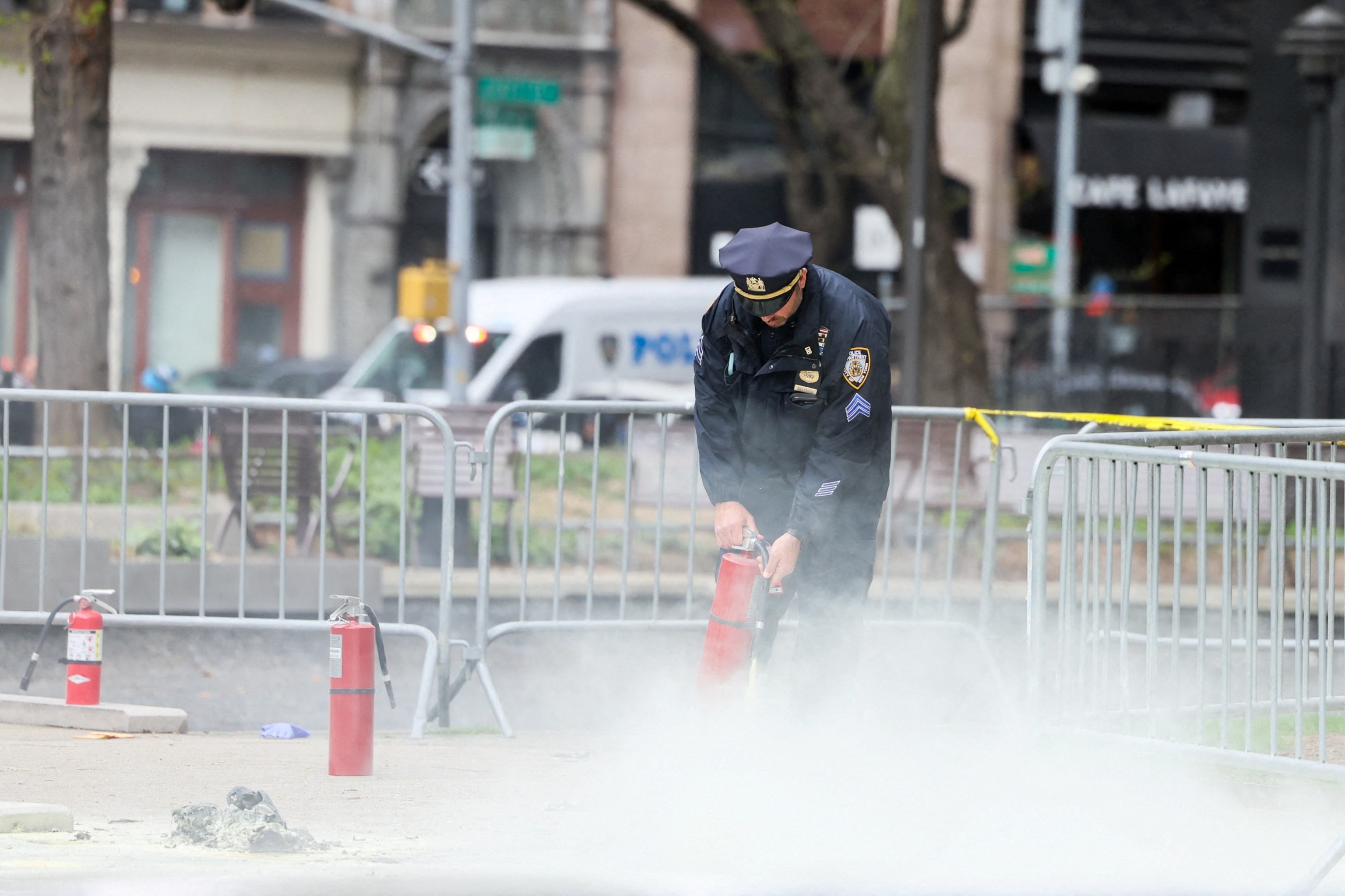 PHOTO: A police officer uses a fire extinguisher as emergency personnel respond to a report of a person covered in flames, outside the courthouse where former President Donald Trump's  trial in New York, April 19, 2024. 
