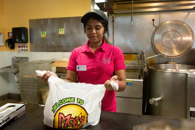 A Moe's Southwest Grill employee bags up a carry-out order Wednesday, March 25, 2020.