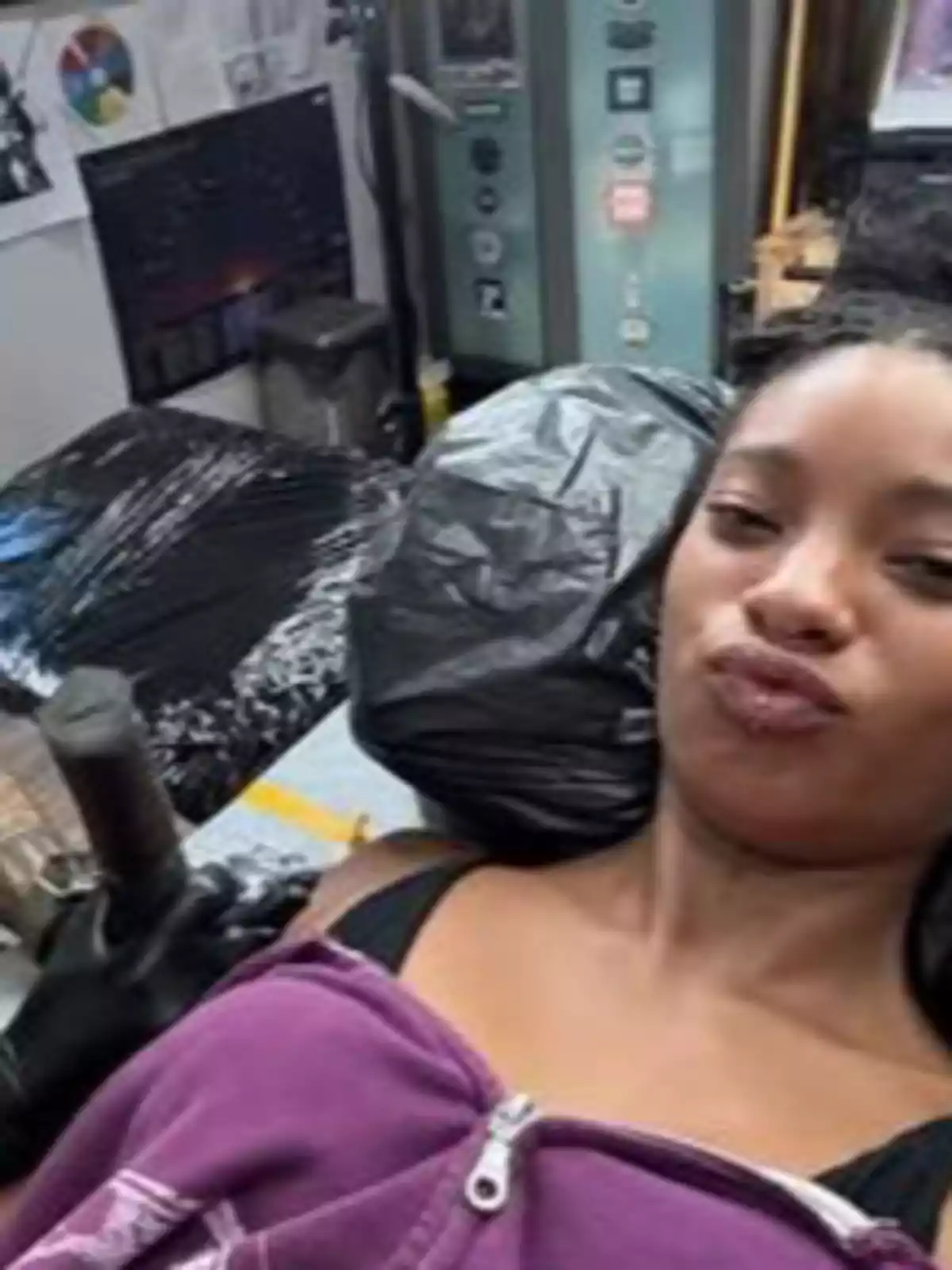 Woman lying on a stretcher inside a tattoo studio with a relaxed expression and wearing a purple sweatjersey Woman lying on a stretcher inside a tattoo studio with a relaxed expression and wearing a purple sweatjersey