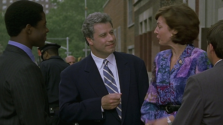 John Travolta as Governor Jack Stanton standing outside with Adrian Lester as Henry Burton and Allison Janney as Miss Walsh in Primary Colors