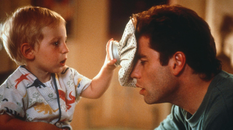 Jacob Haines as Baby Mikey (voiced by Bruce Willis) holding an ice pack to the head of John Travolta as James Ubriacco in Look Who's Talking