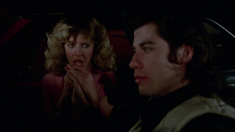 Nancy Allen as Chris Hargensen kisses the hand of John Travolta as Billy Nolan in a car in Carrie