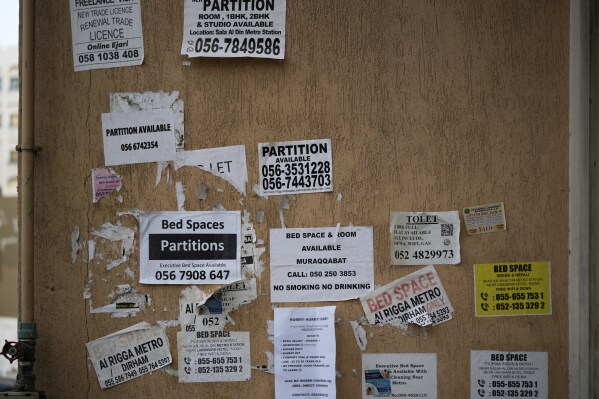 The wall of a building is plastered with advertisements for inexpensive, partitioned housing in Dubai, United Arab Emirates, Friday, July 4, 2025. (AP Photo/Altaf Qadri)