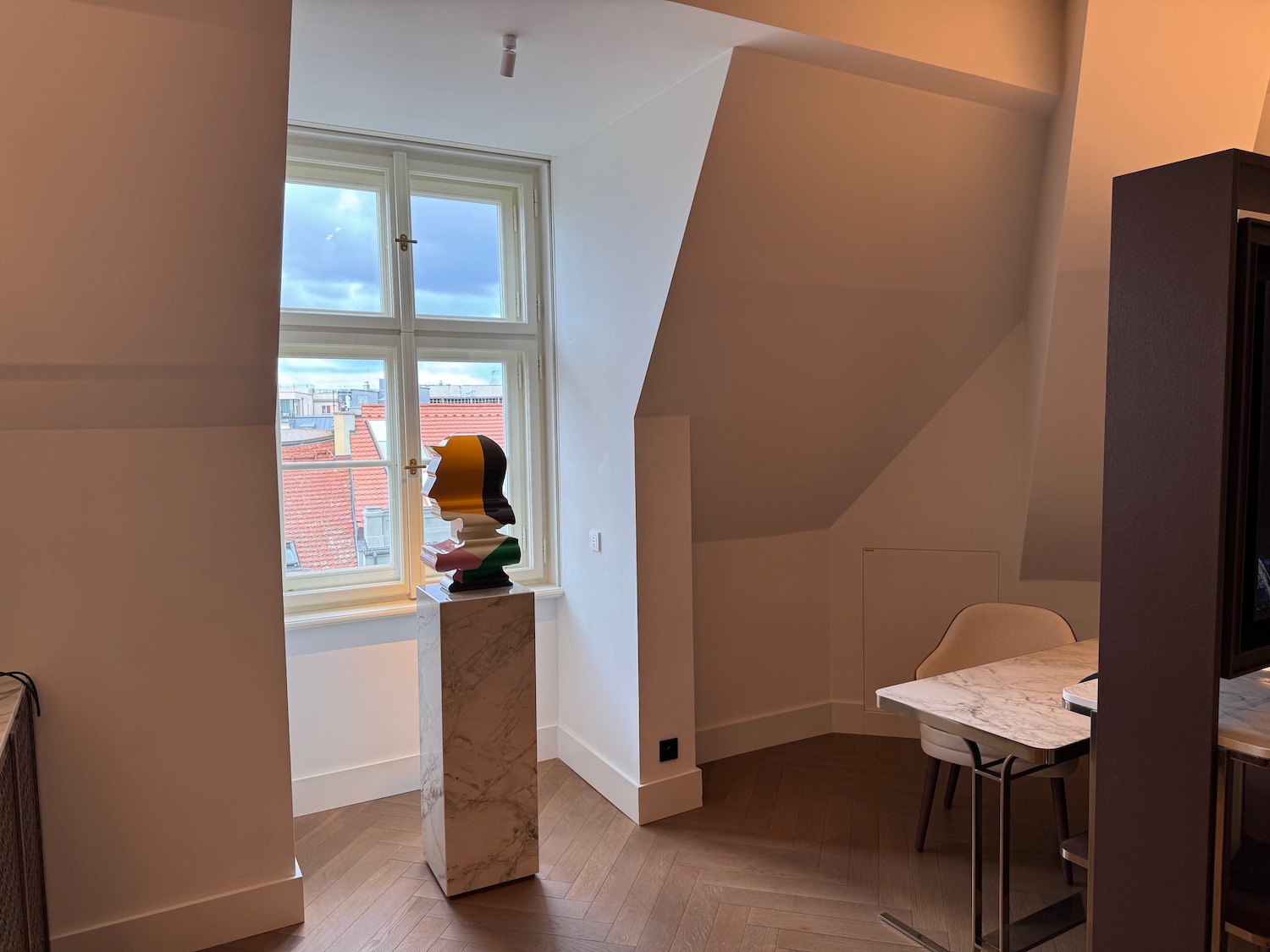 a marble pedestal with a head sculpture in a room with a window