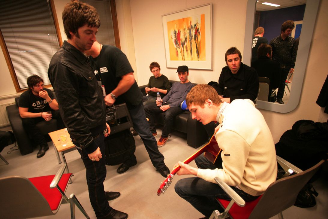 Noel and Liam watch a member of their supporting act, Twisted Wheel, play guitar backstage in 2009 in Amsterdam, ahead of one of the band's last shows before they split up.