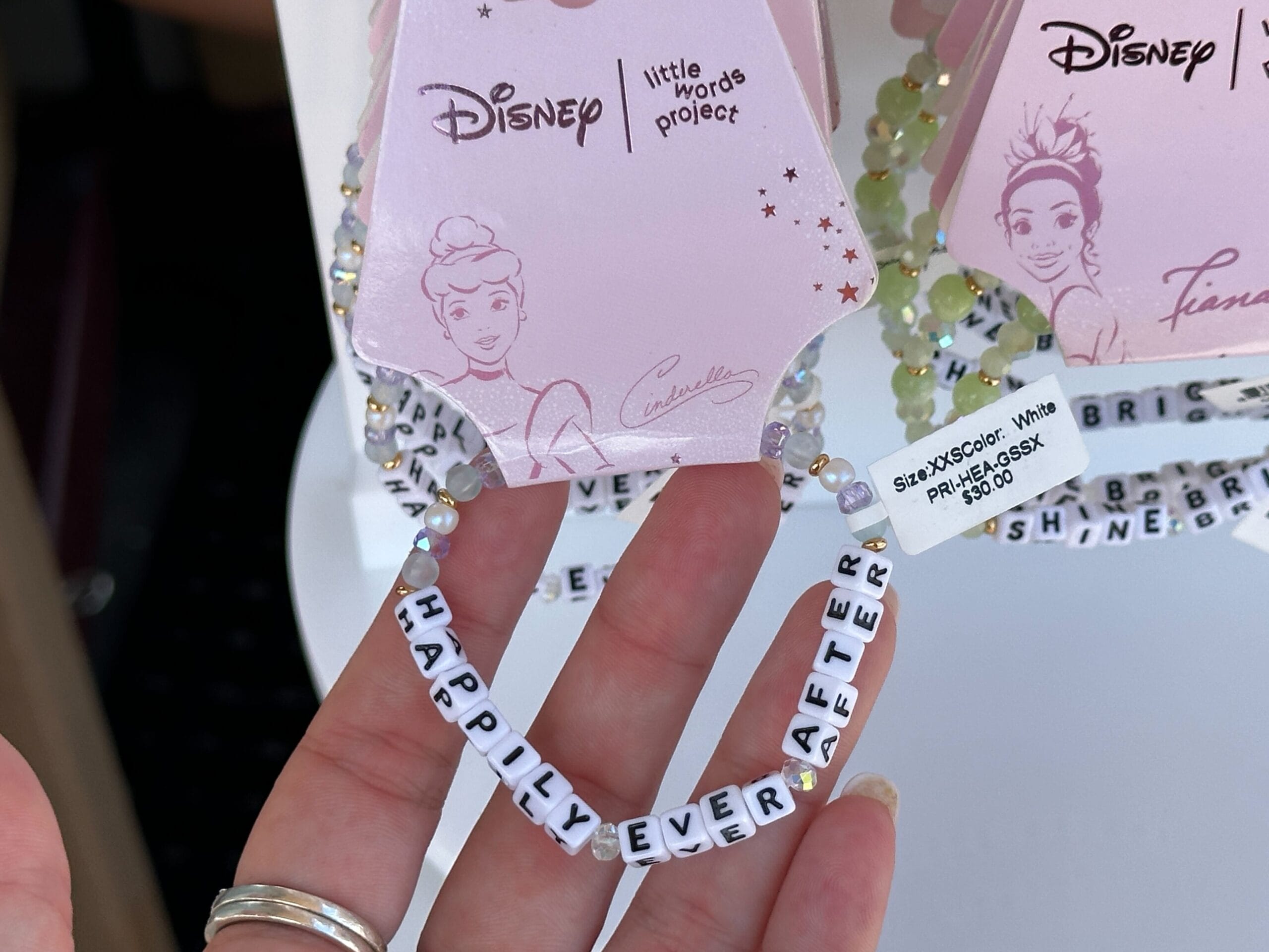 Hand holding a beaded bracelet with white letter beads spelling