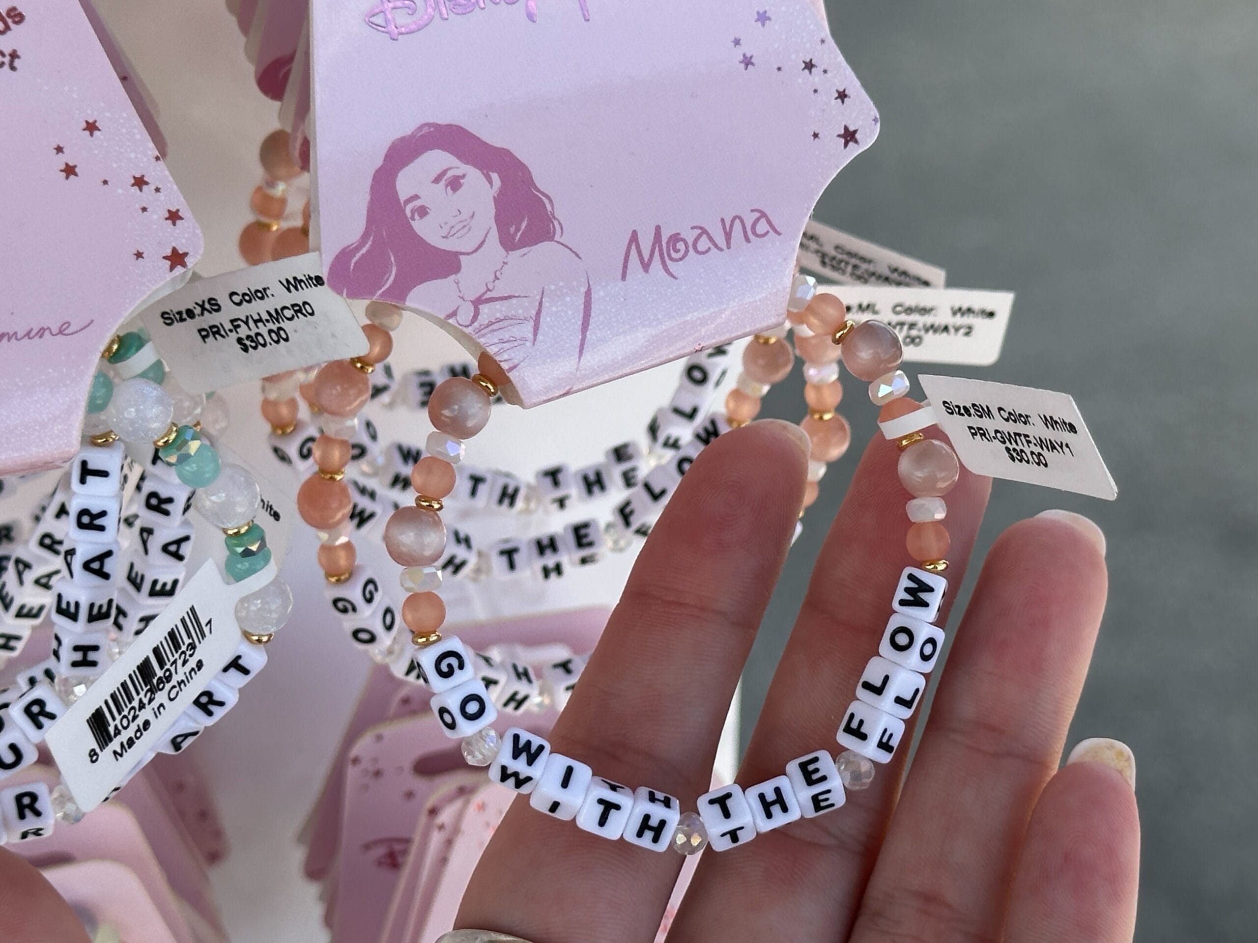 A hand holds a beaded bracelet reading