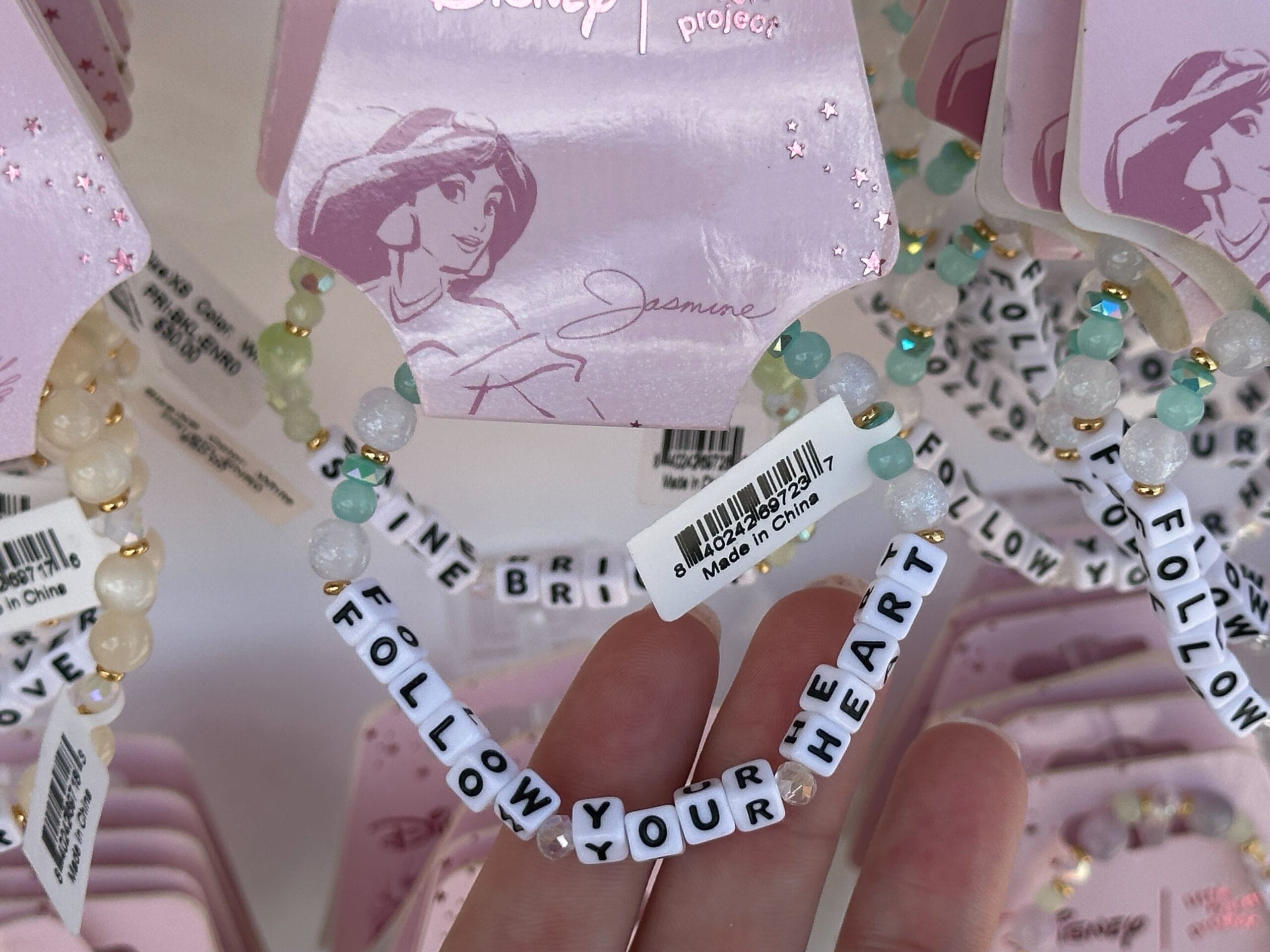 A hand holds a beaded bracelet reading