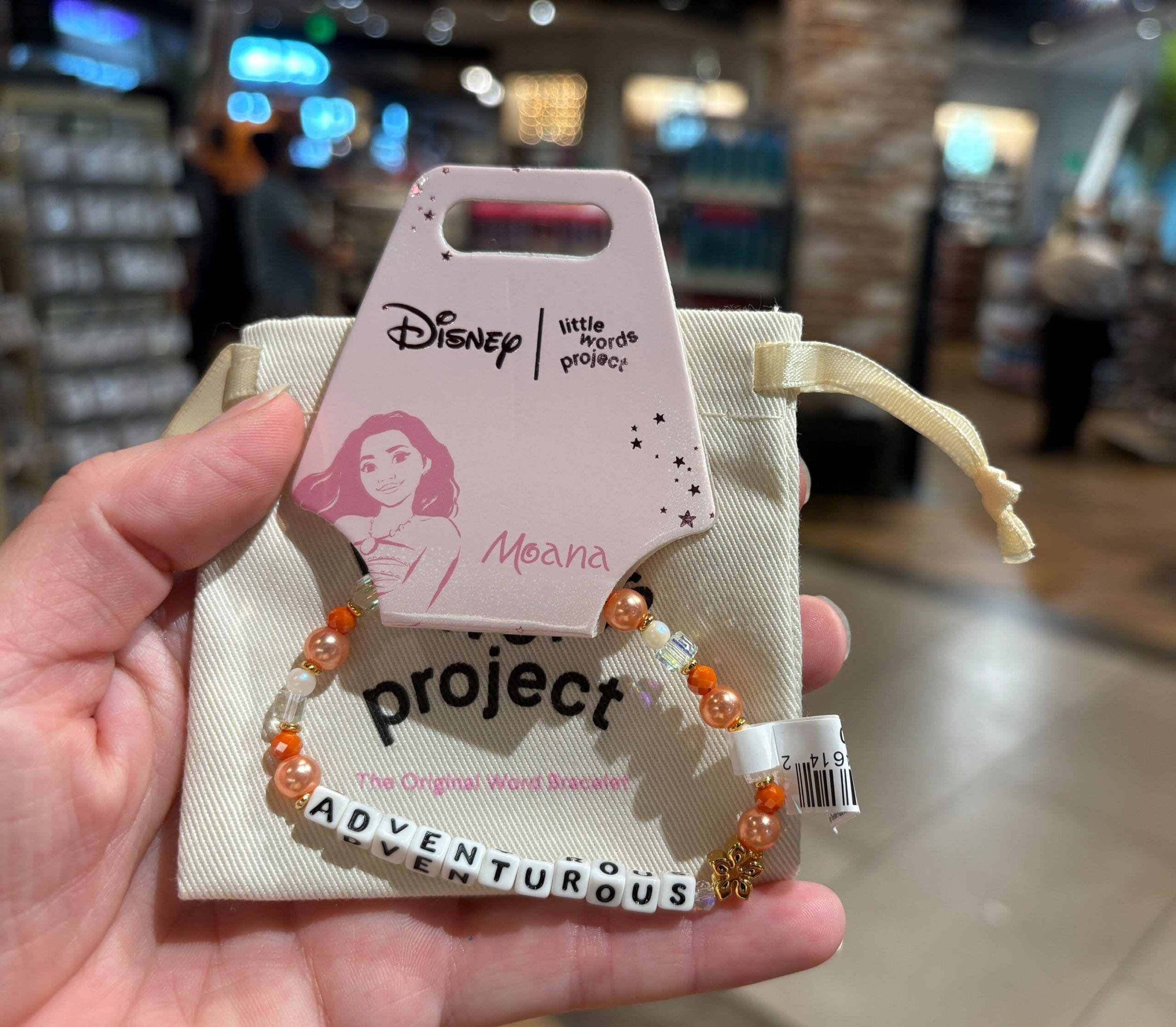 A hand holds a Moana-themed beaded bracelet spelling