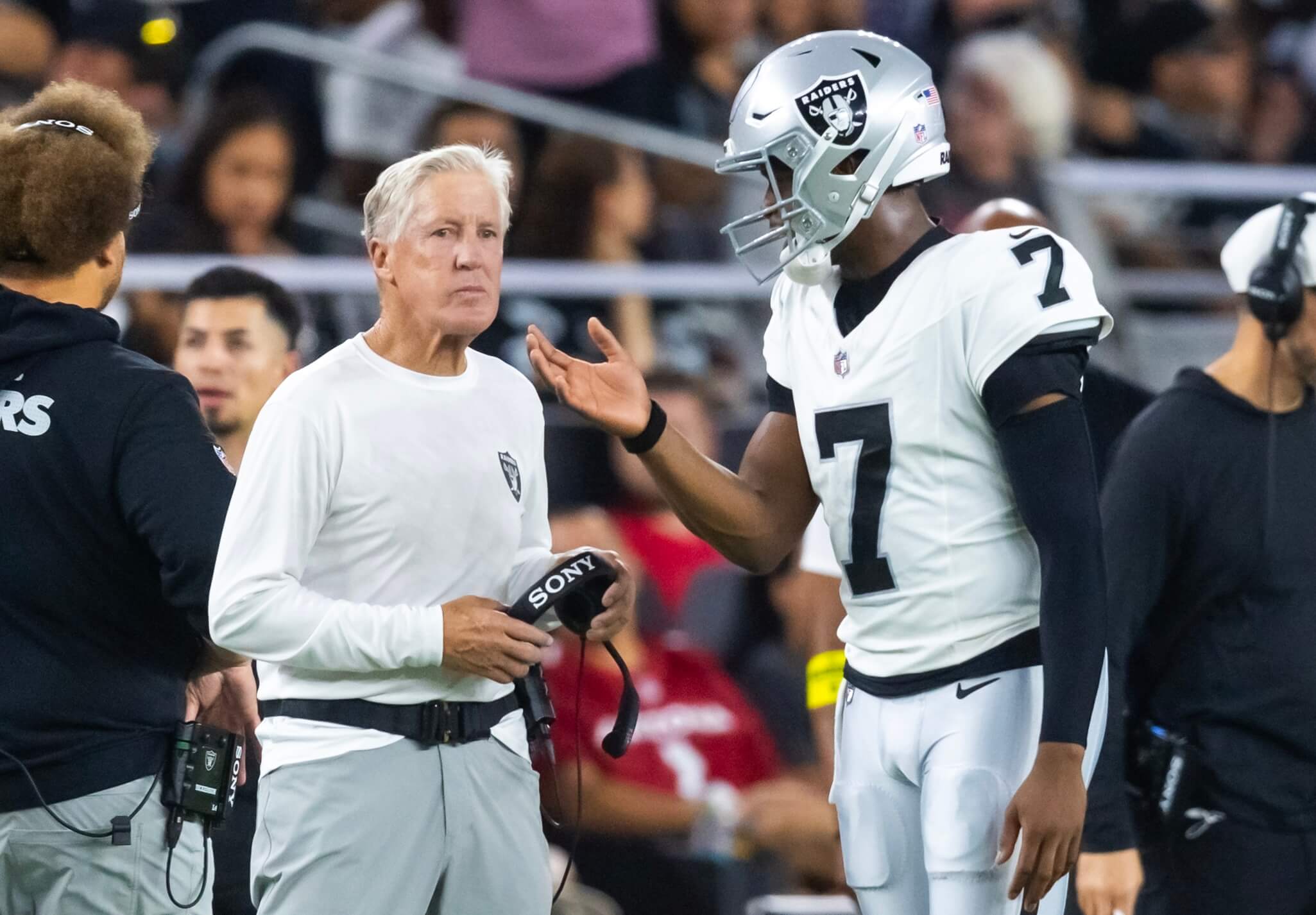Las Vegas Raiders quarterback Geno Smith talks to head coach Pete Carroll against the Arizona Cardinals during a preseason NFL game at State Farm Stadium.
