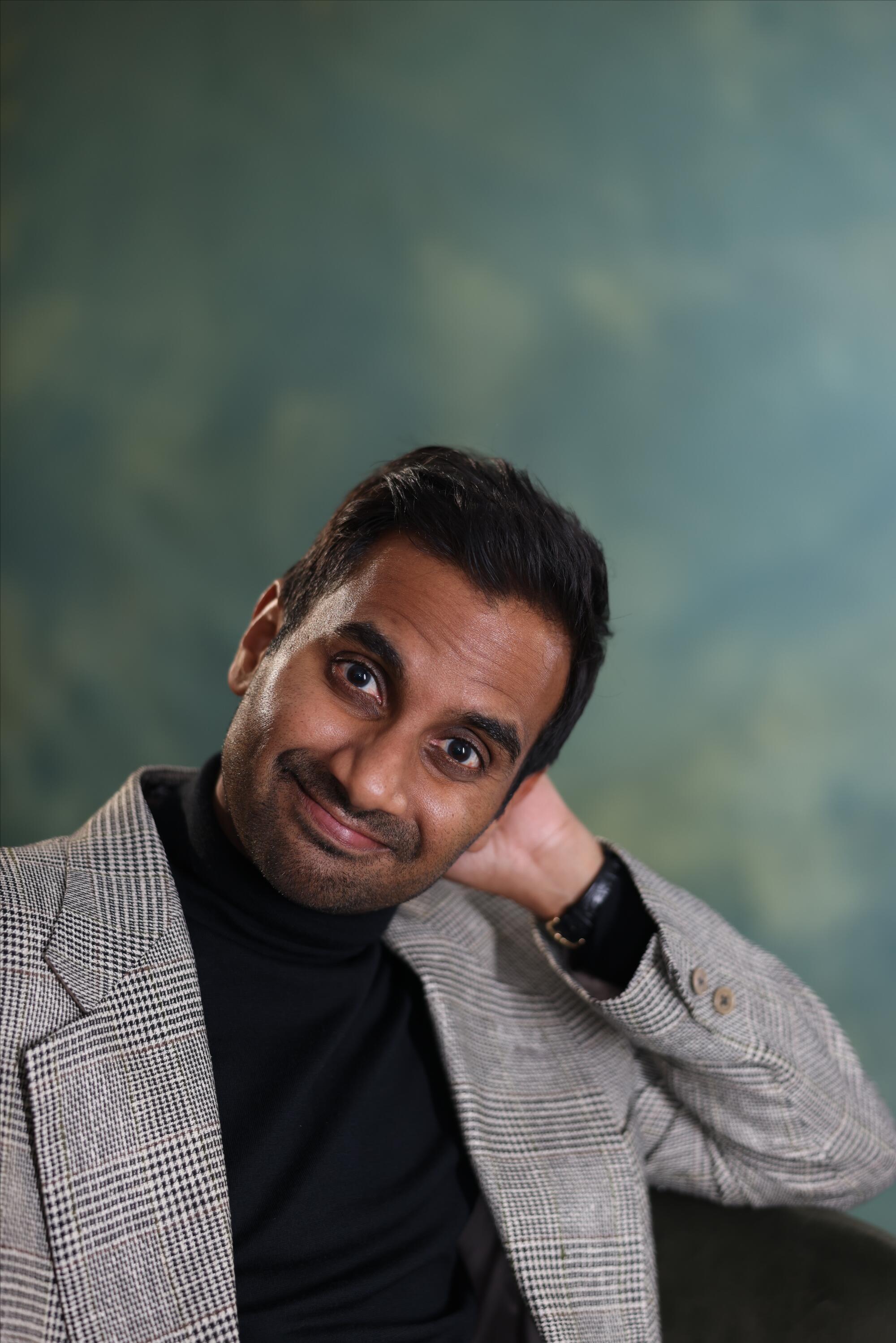 A man in a gray blazer smiles.
