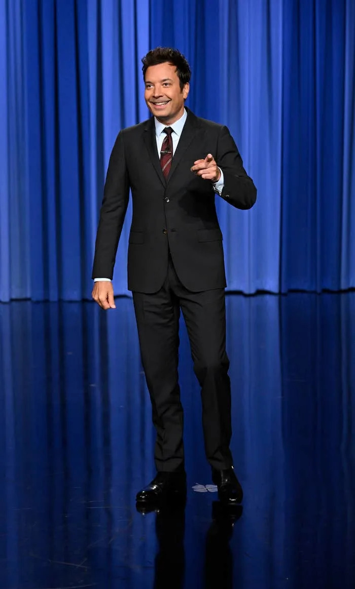 Jimmy Fallon on a stage with a curtain backdrop