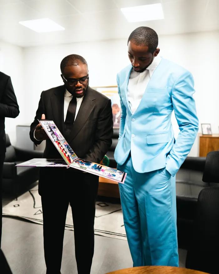 Jonathan Kuminga and an unnamed person look at a photo album together.